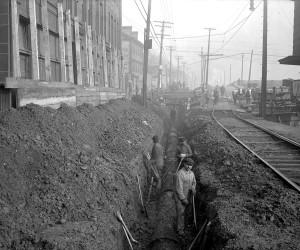 1920 - View of men raising 24-inch cast iron line on E. Ohio St.  715.205056.CP **